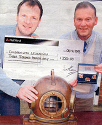 Richard (right) presenting Lloyd (left) with 3000 cheque with part of the famous diving suit in the foreground